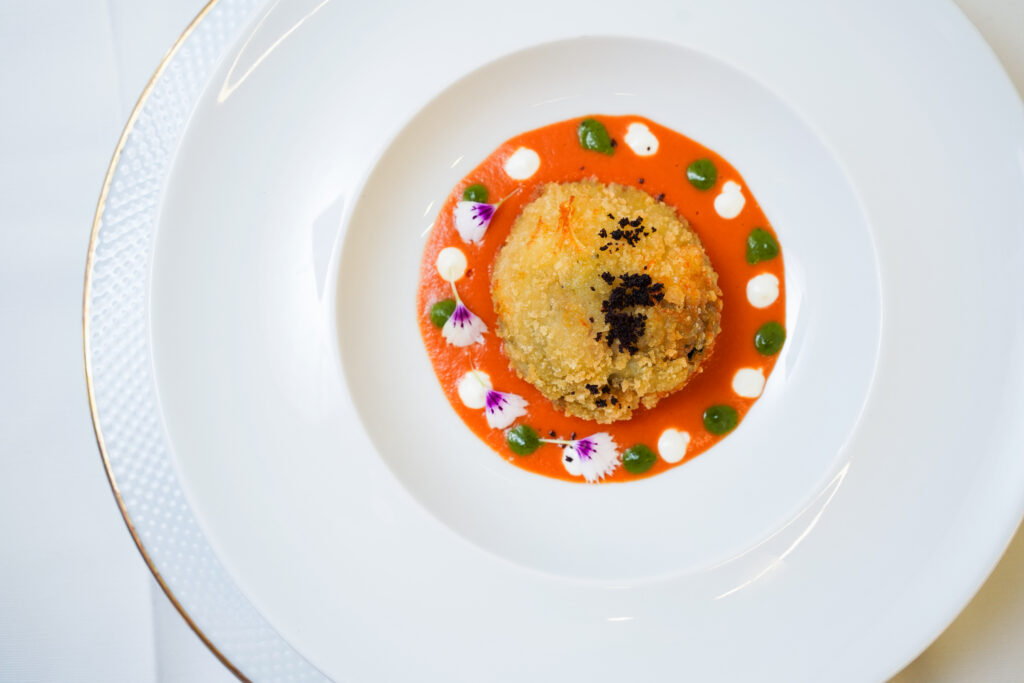 “Crocchetta gourmet su crema rossa con salse decorative e fiori eduli – Rama Eventi”