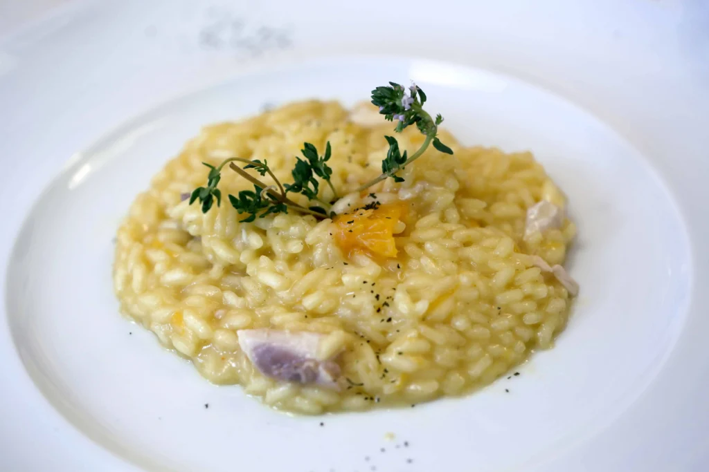 “Risotto cremoso gourmet con erbe aromatiche e decorazione di stagione – catering Rama Eventi”