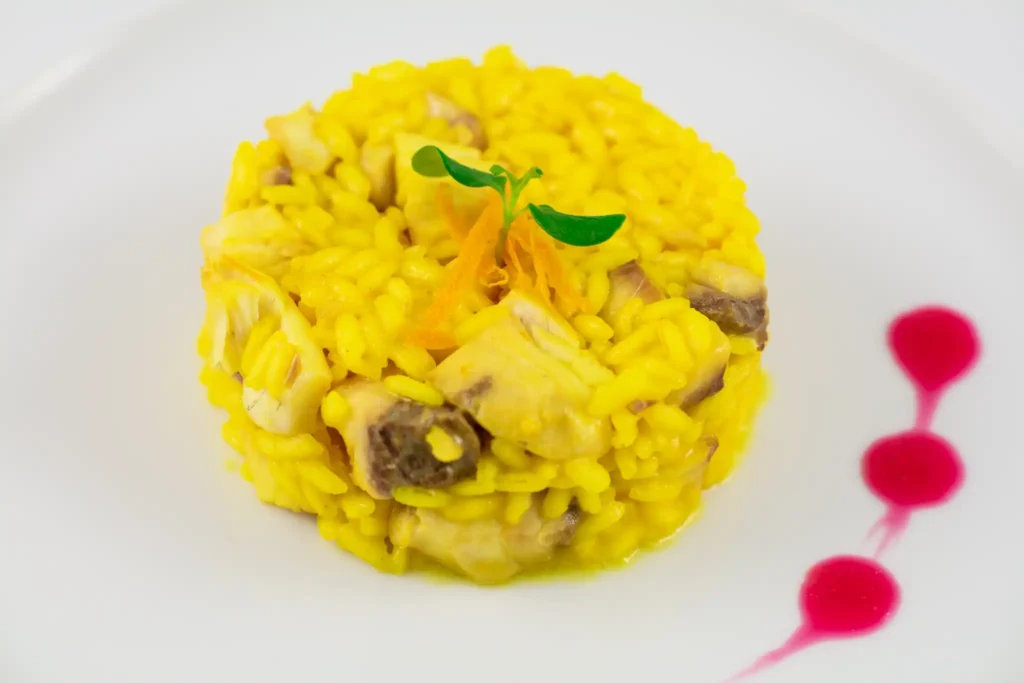 “Risotto allo zafferano con decorazione floreale ed erbe aromatiche – catering Rama Eventi”